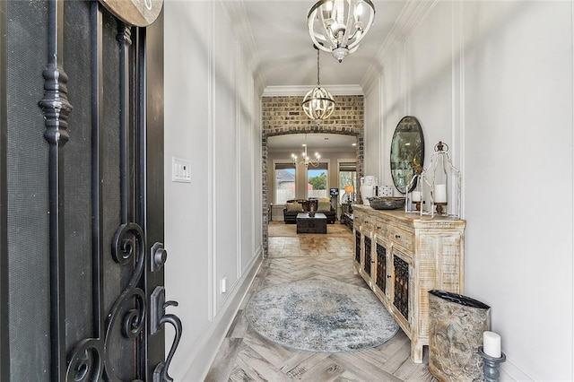 entryway featuring crown molding, arched walkways, baseboards, and a chandelier