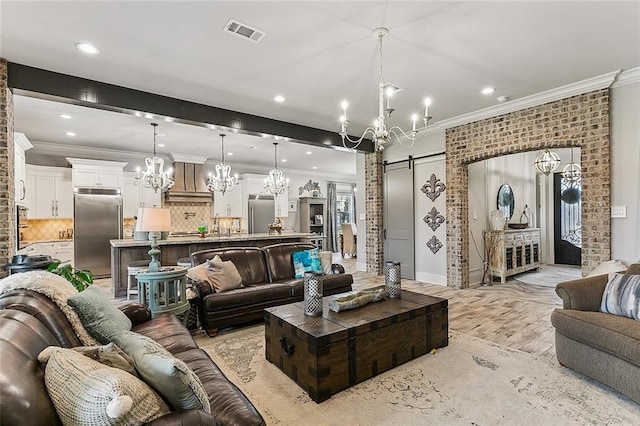 living room with an inviting chandelier, a barn door, recessed lighting, visible vents, and ornamental molding