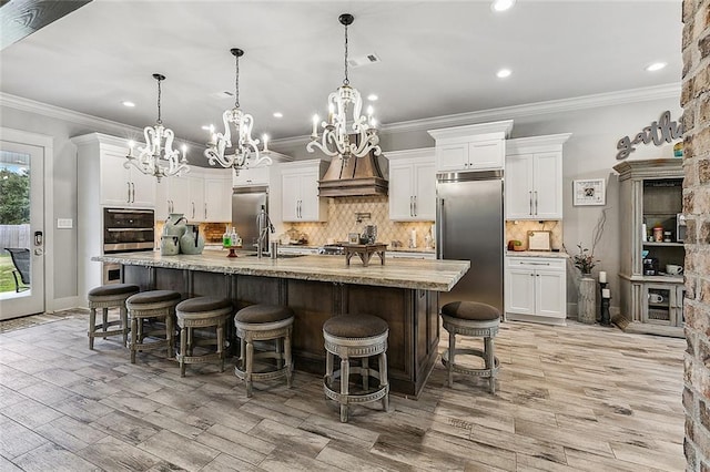 kitchen with visible vents, premium range hood, tasteful backsplash, a notable chandelier, and stainless steel appliances