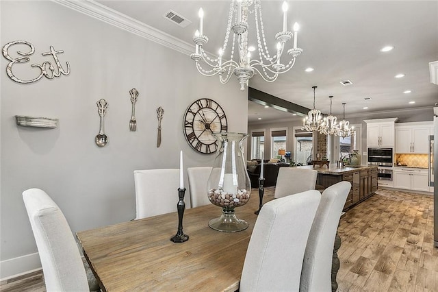 dining area featuring crown molding, a notable chandelier, recessed lighting, light wood-type flooring, and visible vents
