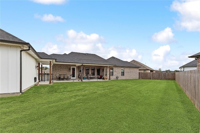 rear view of property featuring a lawn, a patio, and a fenced backyard