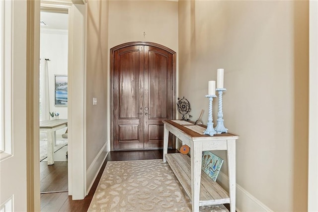 doorway featuring baseboards and dark wood-style flooring