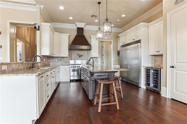 kitchen featuring light stone countertops, a sink, custom exhaust hood, wine cooler, and premium appliances