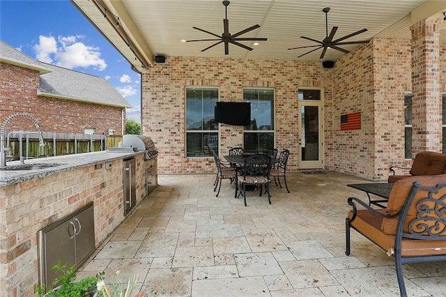 view of patio / terrace featuring ceiling fan, exterior kitchen, a sink, and a grill
