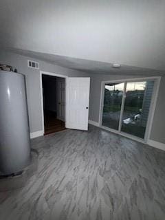 unfurnished room with baseboards, water heater, vaulted ceiling, and visible vents