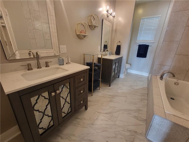 bathroom featuring a sink, marble finish floor, tiled tub, and toilet