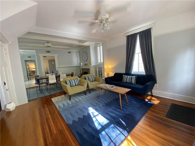 living area with baseboards, a ceiling fan, wood finished floors, and a fireplace