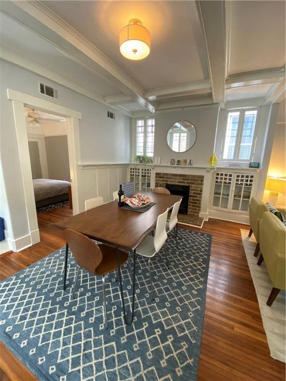 dining space with visible vents, a wealth of natural light, wood finished floors, and coffered ceiling