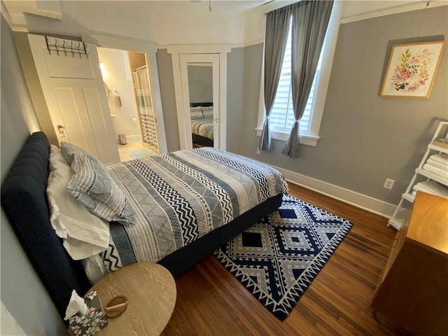bedroom featuring baseboards, ensuite bath, and wood finished floors