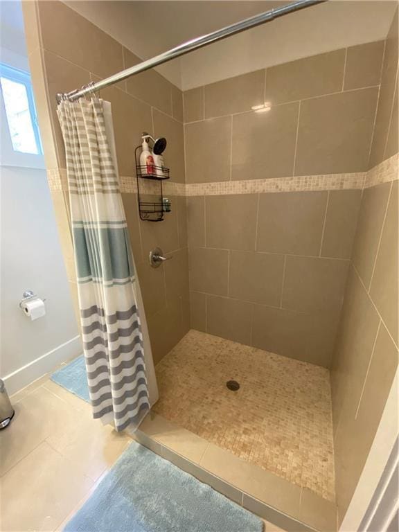 bathroom with tile patterned flooring and a tile shower