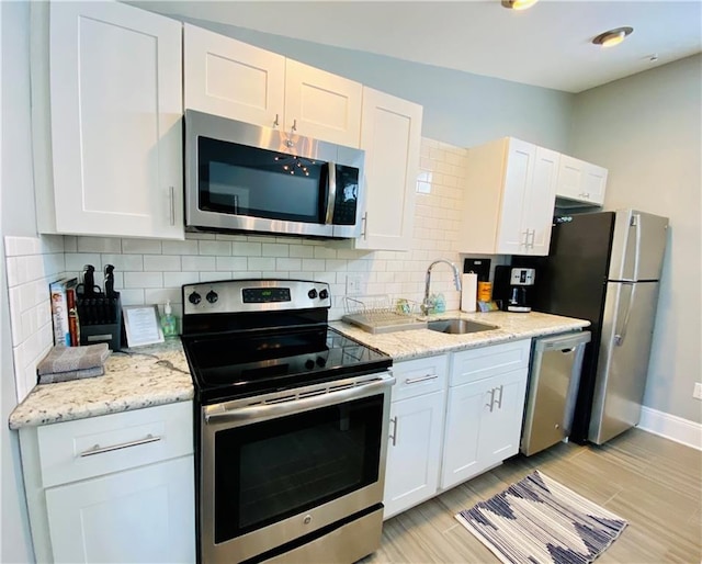 kitchen featuring white cabinetry, appliances with stainless steel finishes, a sink, and tasteful backsplash