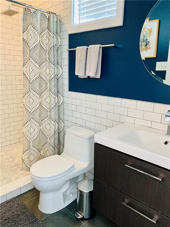 bathroom with vanity, tile walls, a stall shower, and toilet