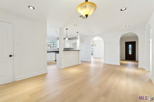 unfurnished living room featuring recessed lighting, arched walkways, light wood-type flooring, and visible vents