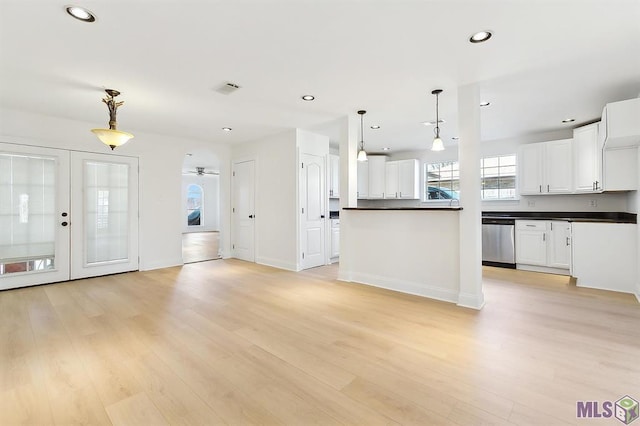 kitchen featuring visible vents, dark countertops, stainless steel dishwasher, white cabinets, and light wood-style floors
