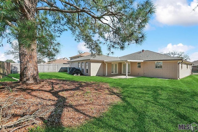 back of property with a lawn, a patio area, fence, and brick siding