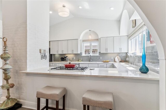 4524 Folse Dr, Metairie, LA 70006 - kitchen featuring backsplash, a sink, a peninsula, stainless steel gas stovetop, and a wealth of natural light