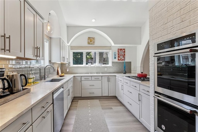 4524 Folse Dr, Metairie, LA 70006 - kitchen featuring light countertops, a sink, light wood finished floors, backsplash, and stainless steel appliances
