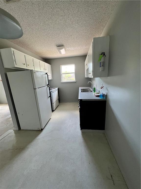 46344 Patti Ln, Hammond, LA 70403 - kitchen featuring freestanding refrigerator, baseboards, a textured ceiling, white cabinets, and a sink