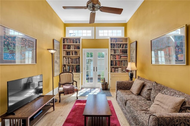 living room featuring crown molding, ceiling fan, wood finished floors, and a towering ceiling