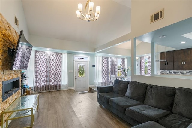 living area featuring a notable chandelier, high vaulted ceiling, visible vents, and wood finished floors