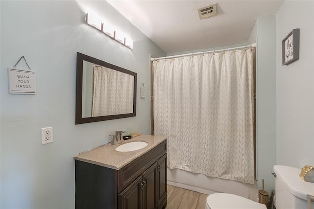 full bath featuring vanity, toilet, a shower with shower curtain, wood finished floors, and visible vents