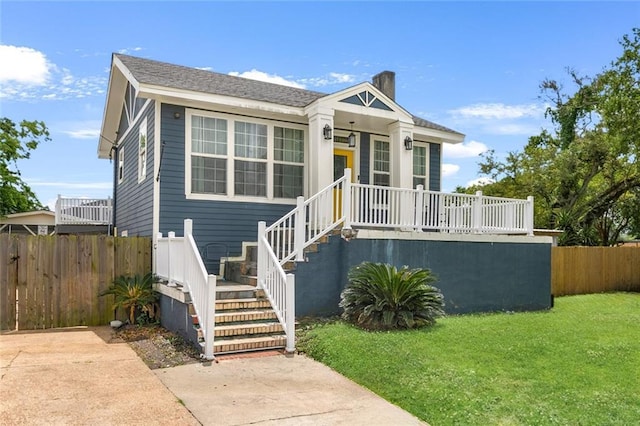bungalow-style house featuring a porch, fence, a chimney, and a front yard