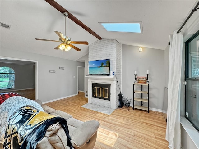 115 Spruce Cir, Slidell, LA 70458 - living area with a brick fireplace, light wood-style floors, ceiling fan, and a skylight