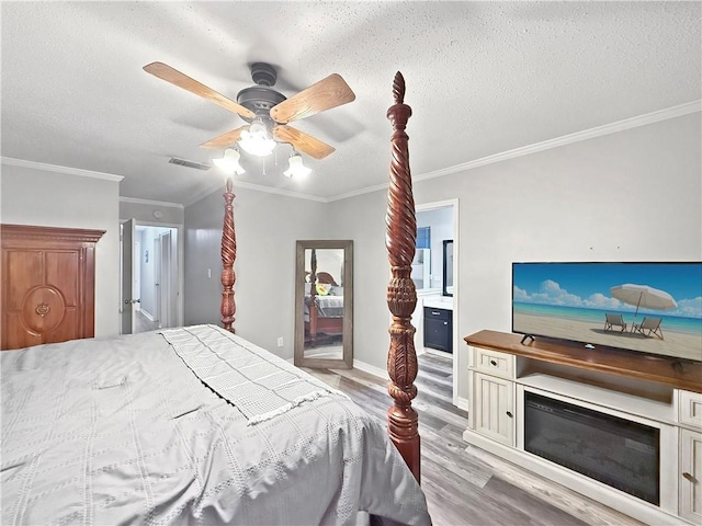 115 Spruce Cir, Slidell, LA 70458 - bedroom featuring light wood-style flooring, ornamental molding, a textured ceiling, connected bathroom, and ceiling fan