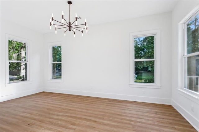 unfurnished dining area featuring baseboards, light wood-style flooring, and a notable chandelier
