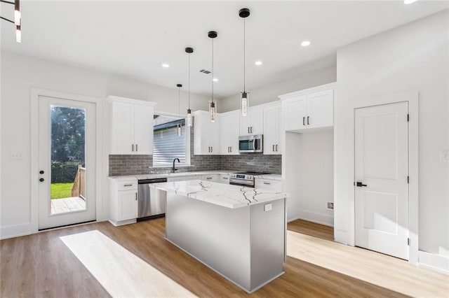 kitchen with appliances with stainless steel finishes, light wood-type flooring, and a wealth of natural light