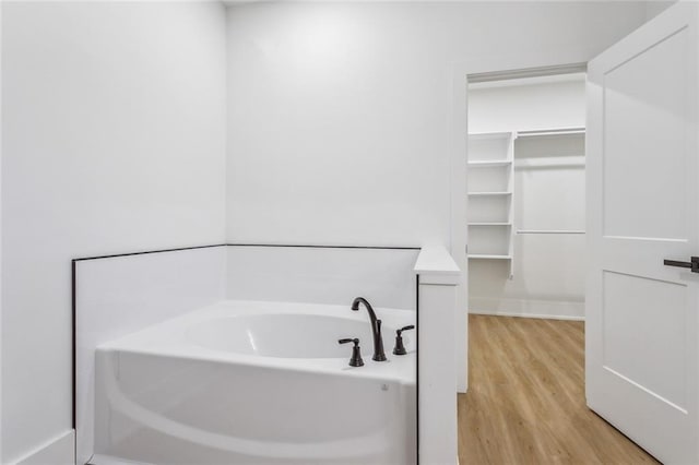 full bath with a garden tub and wood finished floors
