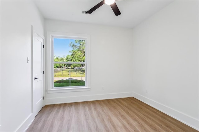 spare room with baseboards, ceiling fan, light wood finished floors, and visible vents