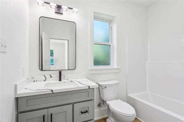 bathroom with vanity, plenty of natural light, baseboards, and toilet