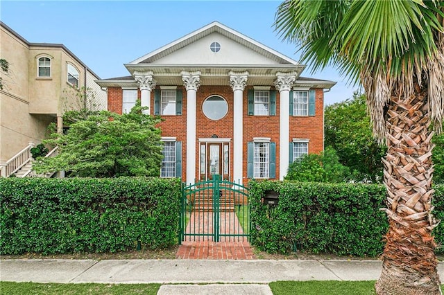 neoclassical / greek revival house featuring brick siding, a gate, and fence private yard