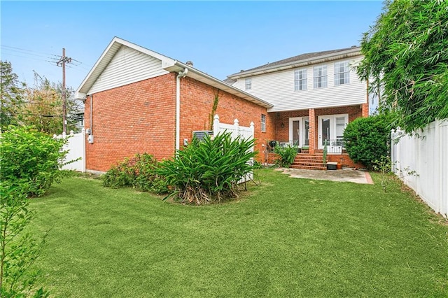 rear view of property featuring a lawn, brick siding, and fence