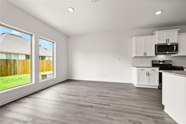 kitchen featuring backsplash, stainless steel appliances, white cabinetry, and wood finished floors