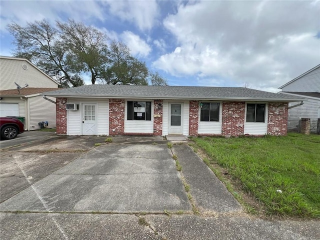 ranch-style house with a shingled roof, a front lawn, brick siding, an AC wall unit, and central air condition unit