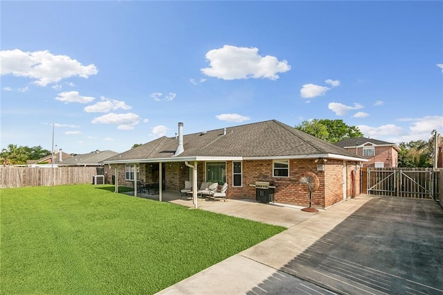 back of house with a fenced backyard, a shingled roof, a yard, and a patio area