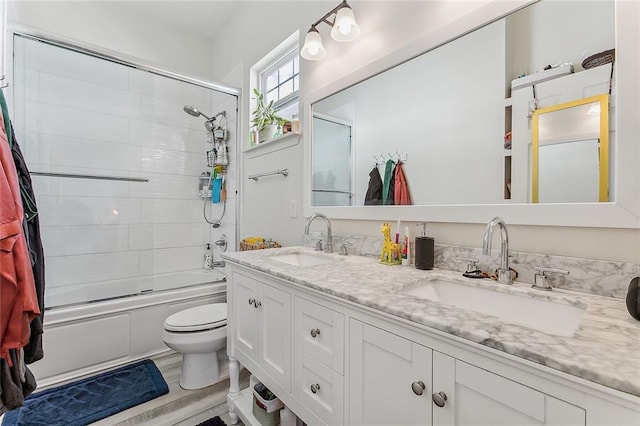 full bathroom with double vanity, toilet, enclosed tub / shower combo, and a sink