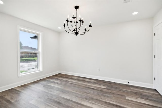unfurnished dining area with recessed lighting, baseboards, a notable chandelier, and wood finished floors
