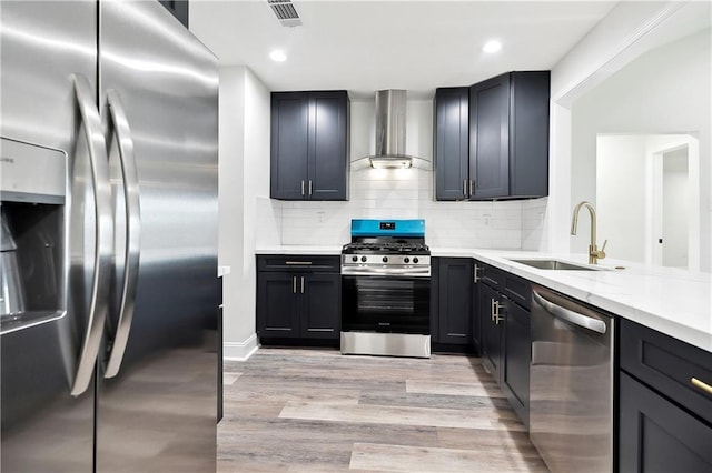 kitchen featuring visible vents, light wood-style floors, wall chimney exhaust hood, a sink, and appliances with stainless steel finishes