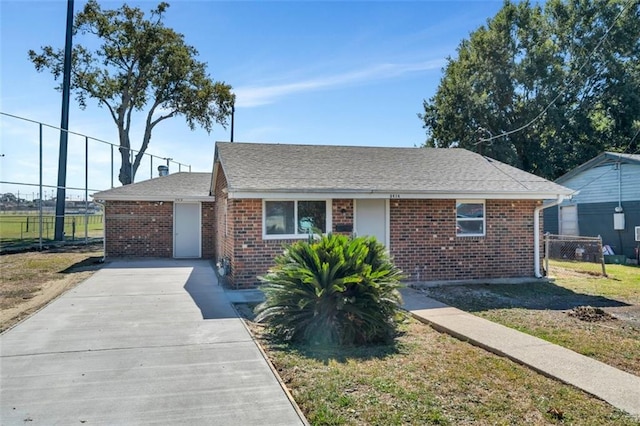 ranch-style home featuring fence, concrete driveway, and brick siding