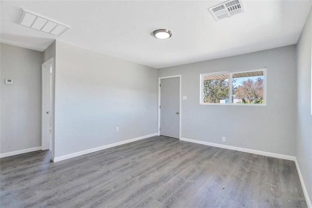 unfurnished room featuring baseboards, wood finished floors, and visible vents