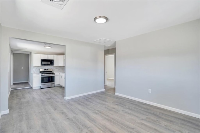 unfurnished living room with visible vents, light wood finished floors, and baseboards