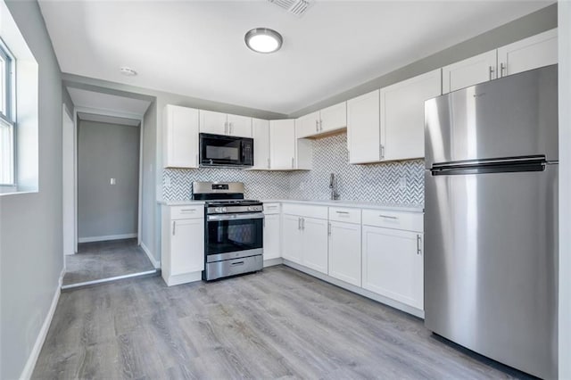 kitchen with white cabinetry, light wood-style floors, appliances with stainless steel finishes, and tasteful backsplash
