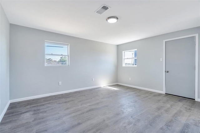 spare room with baseboards, visible vents, and wood finished floors