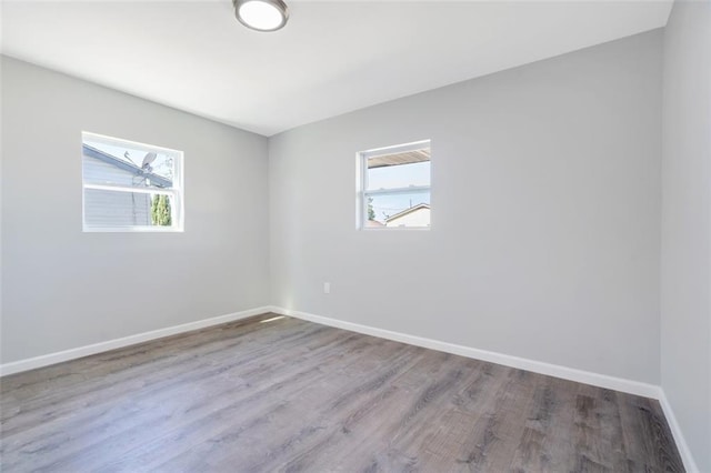 spare room with baseboards and wood finished floors