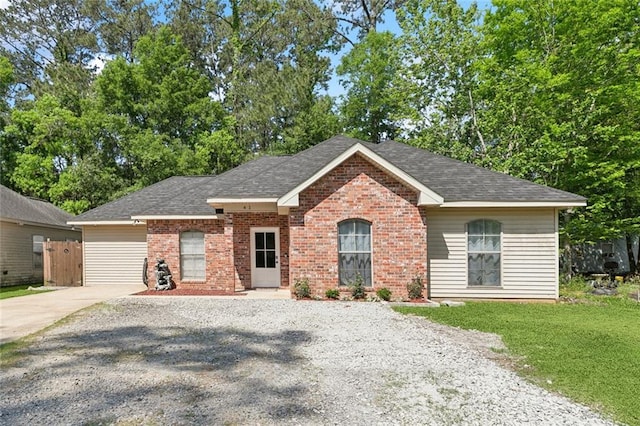 single story home with a shingled roof, gravel driveway, and brick siding