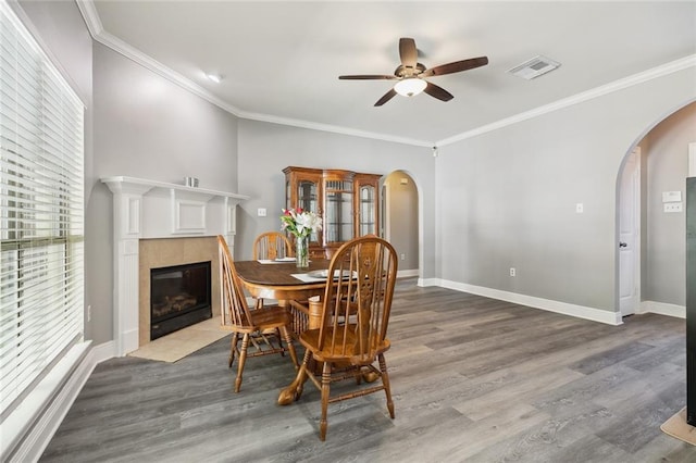 dining space featuring ceiling fan, visible vents, arched walkways, wood finished floors, and baseboards