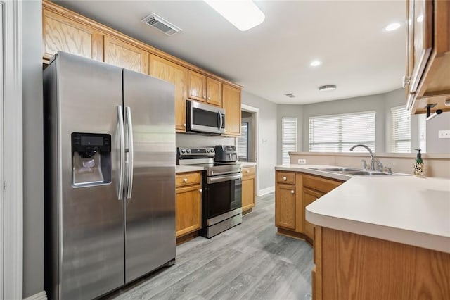 kitchen featuring visible vents, light wood-type flooring, light countertops, a sink, and stainless steel appliances